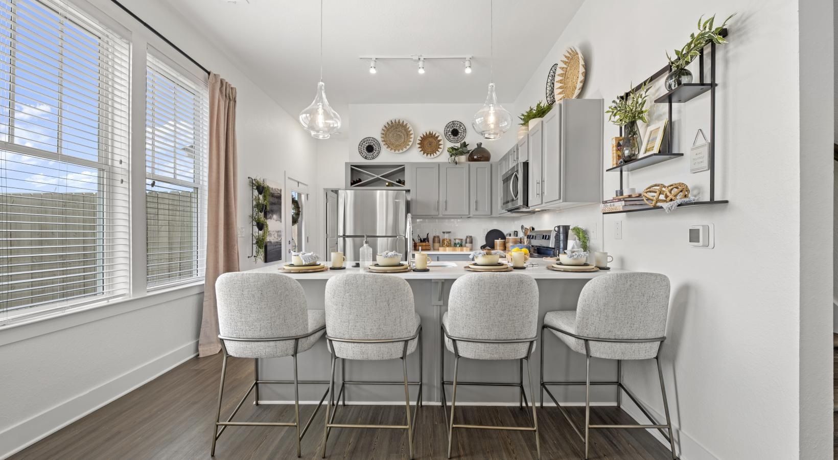 Bright modern kitchen with an island, pendant lights, and grey cabinets.