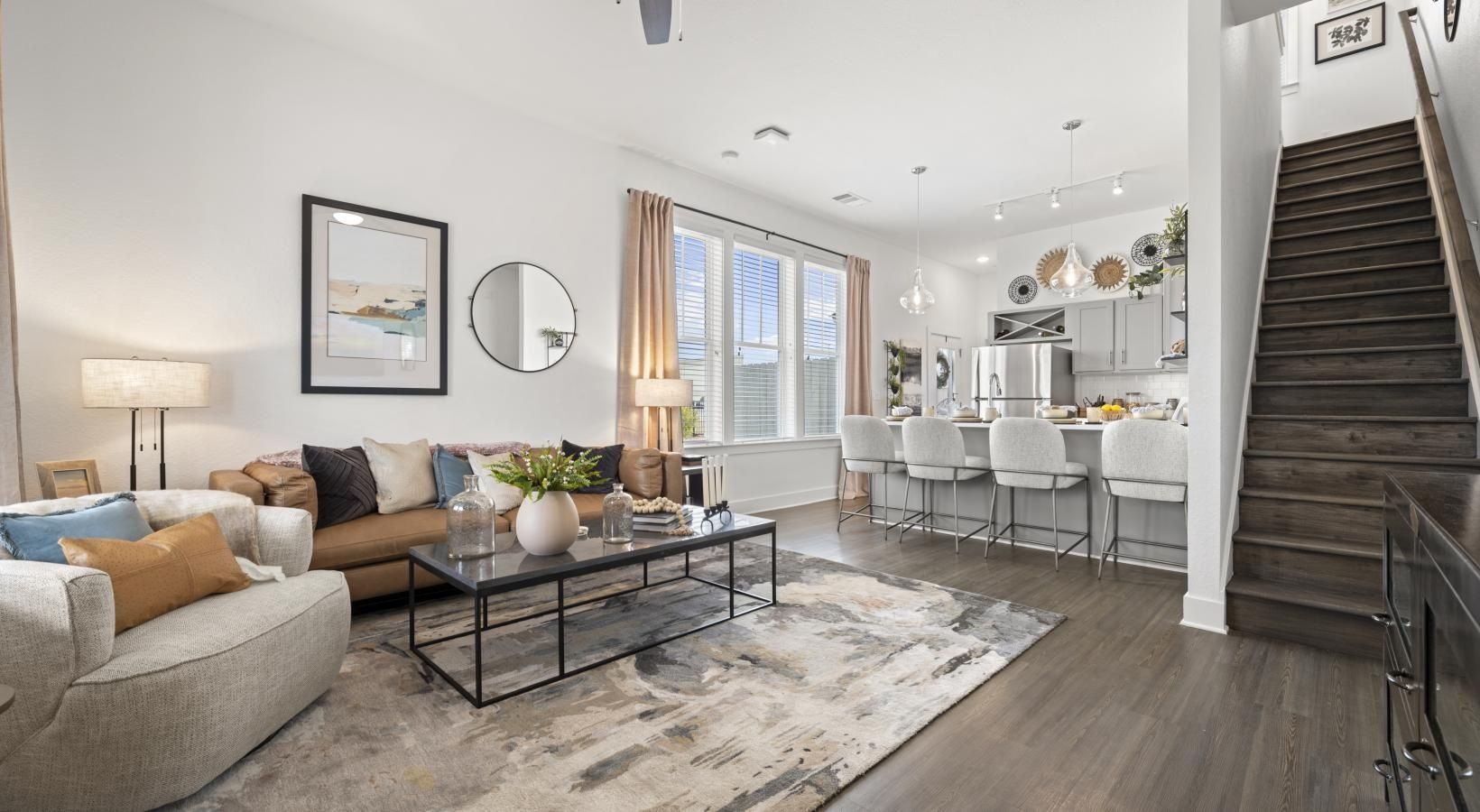 Open-concept living area with sofa, coffee table, kitchen island, and staircase.