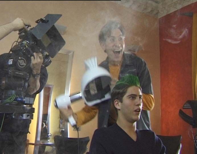 Werbefilmdreh Friseur nimmt einen Helm von Kunde  mit grünen Haaren ab. Es steigt Rauch auf- 
