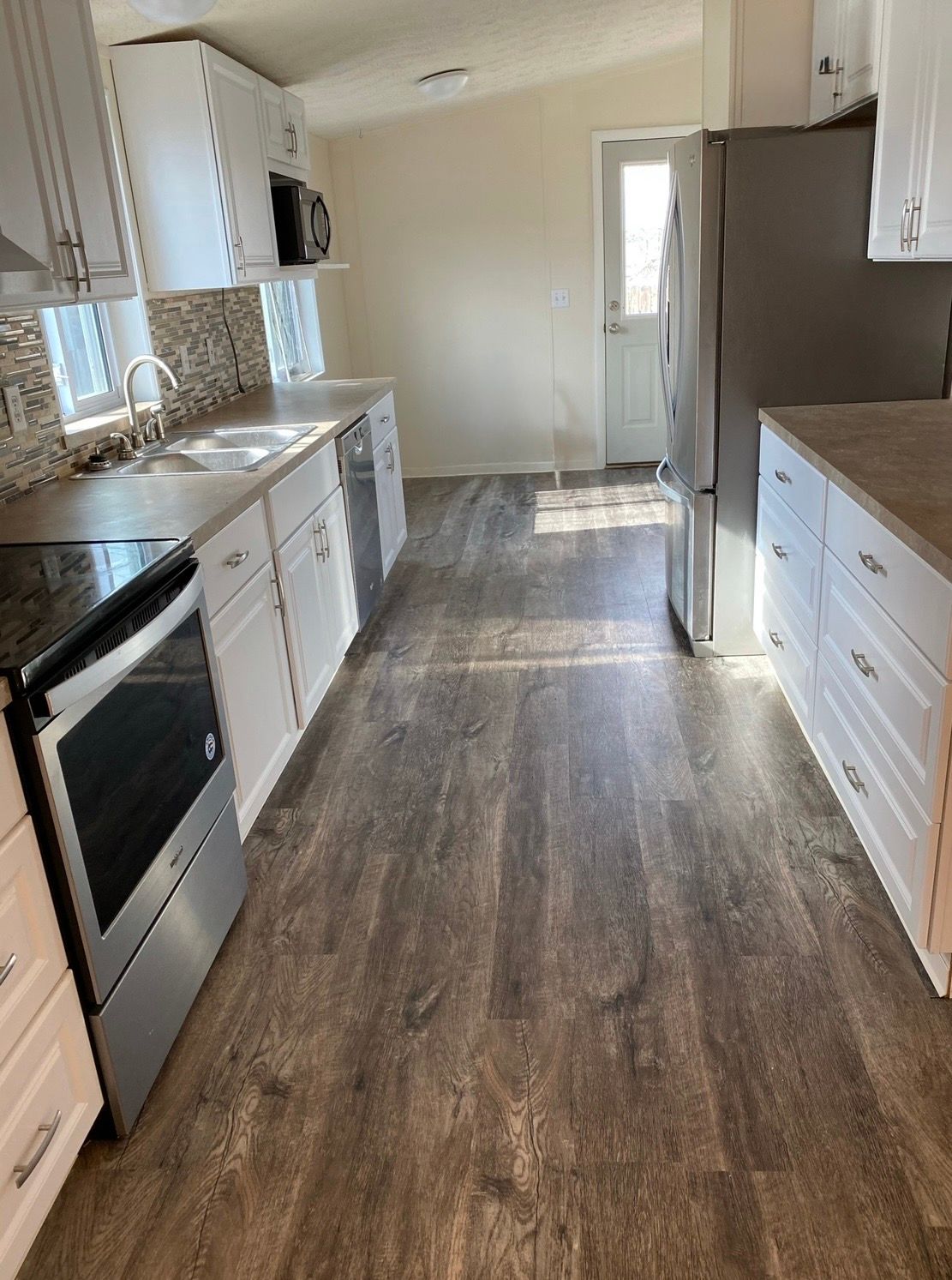 Kitchen with white cabinets, stainless steel appliances, and wood-look flooring.