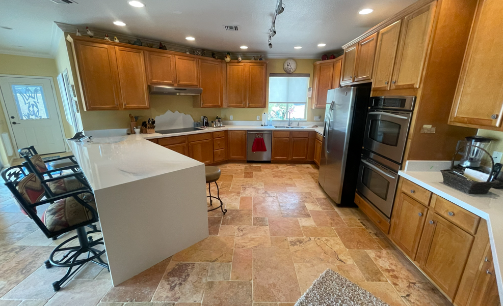 Kitchen with wooden cabinets, stainless steel appliances, and a white countertop island.