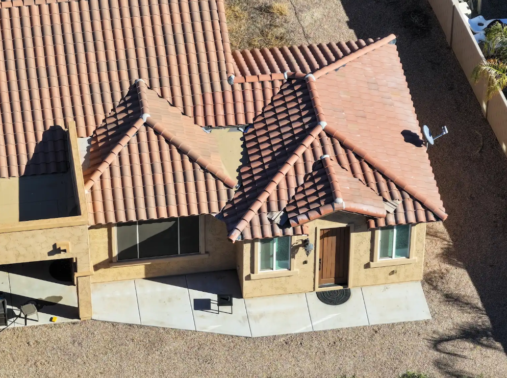 Tan house with red tile roof, concrete walkway, and gravel yard.