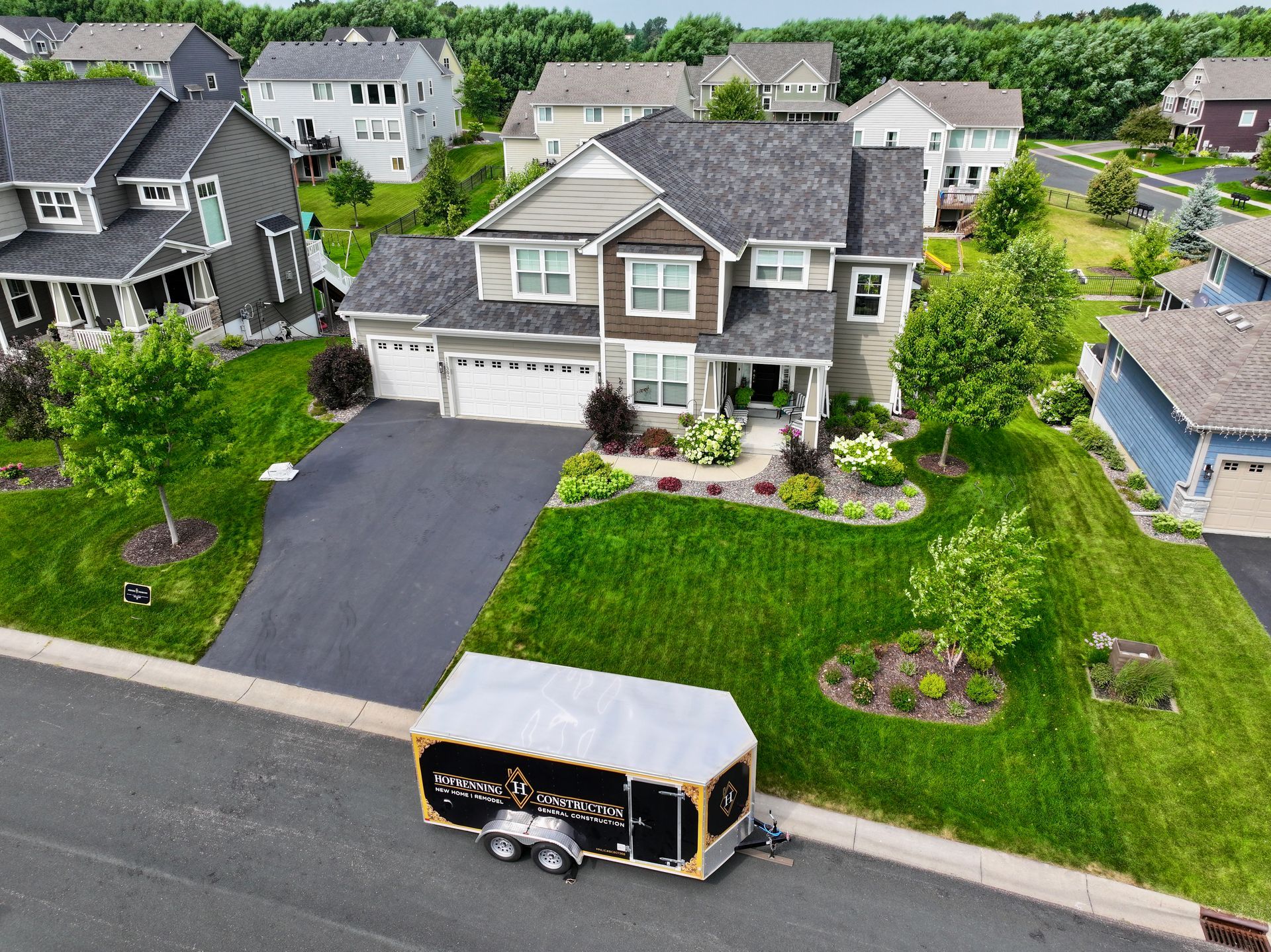 Suburban house with a trailer parked in front on a sunny day.