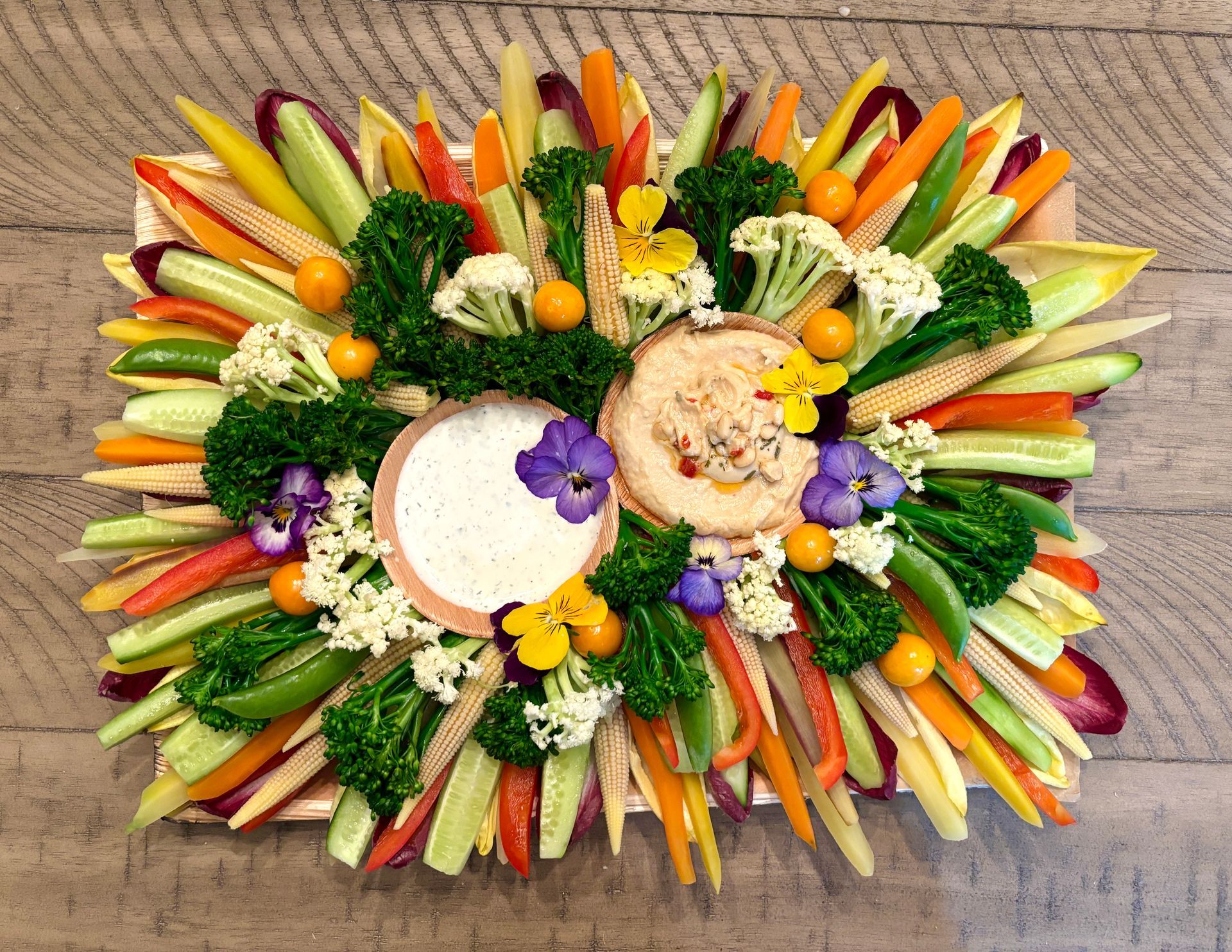 Vegetable platter with two dips, colorful arrangement of carrots, broccoli, and other vegetables.