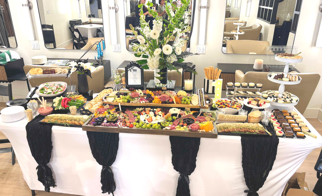 Charcuterie grazing table with cheeses, meats, crackers, fruits, and vegetables, dedserts arranged on a white table.
