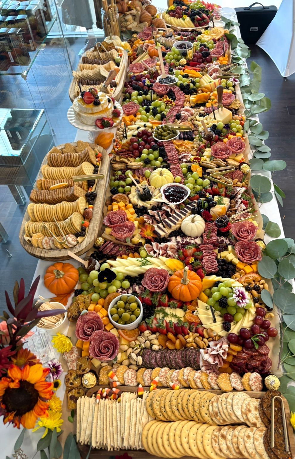 A long table topped with charcuterie, cheese,  lots of food and flowers.