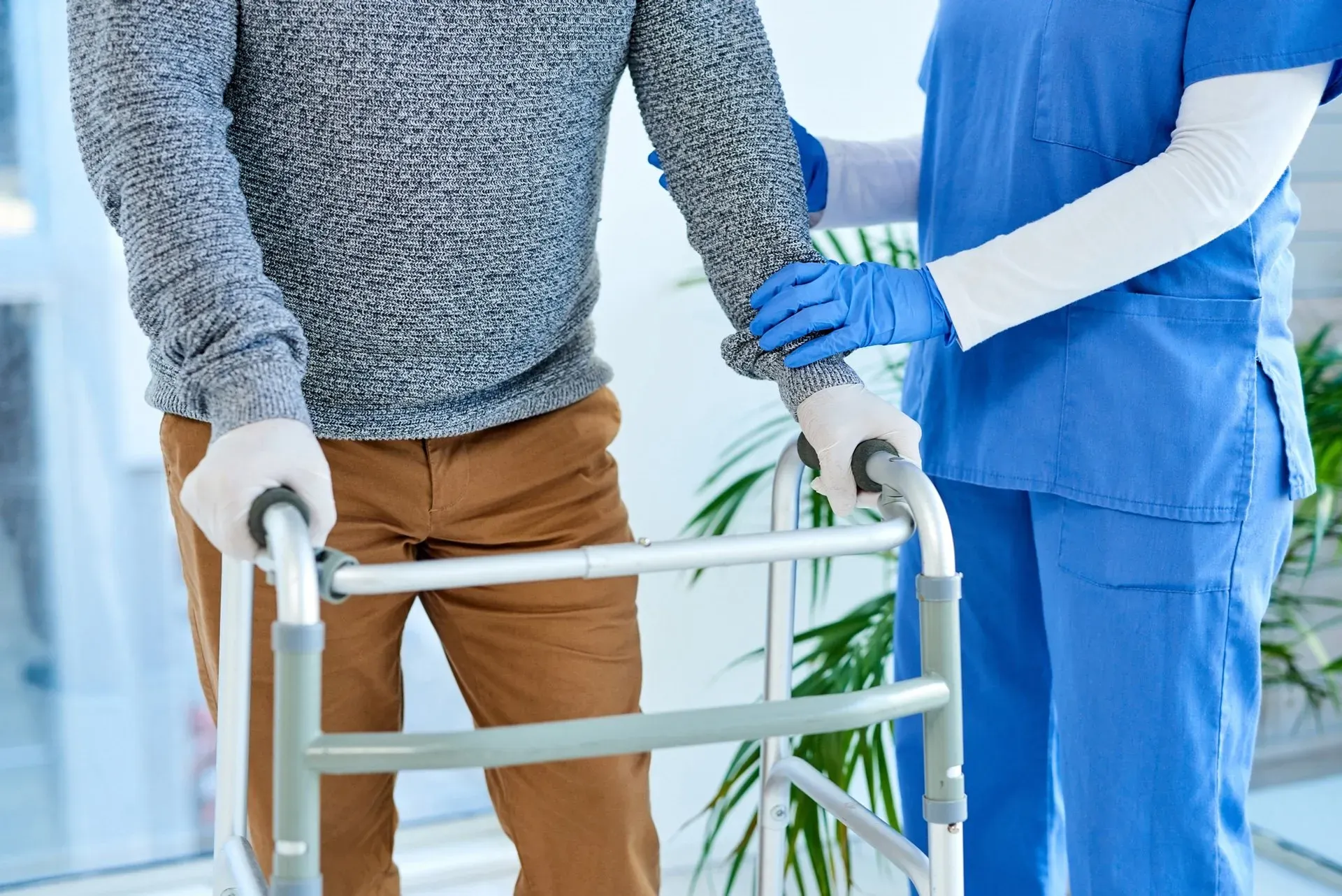 A nurse is helping an elderly man with a walker.