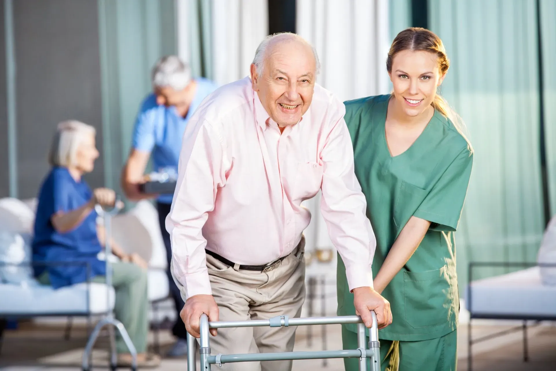 An elderly man is using a walker with a nurse standing next to him.