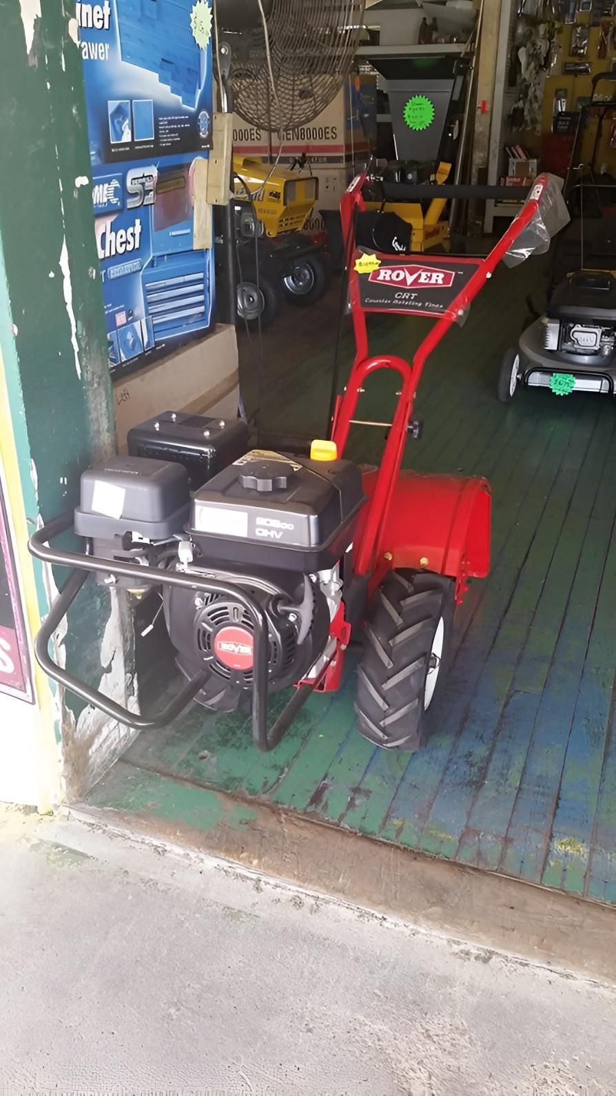A Red Tractor Is Parked In A Garage Next To A Lawn Mower — Harry's Mower Repairs In Bundaberg North, QLD