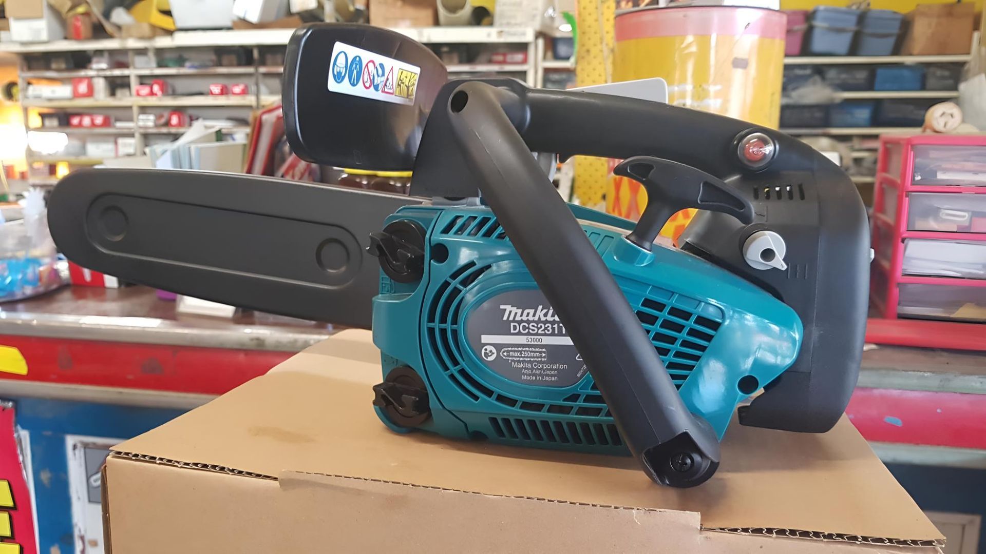 A Chainsaw Is Sitting On Top Of A Cardboard Box In A Store — Harry's Mower Repairs In Bundaberg North, QLD