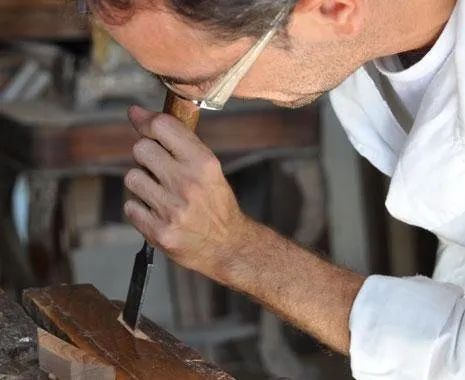 Un uomo sta intagliando un pezzo di legno con uno scalpello.