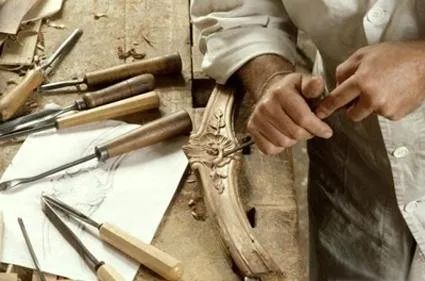 Un uomo sta intagliando un pezzo di legno su un tavolo di legno.