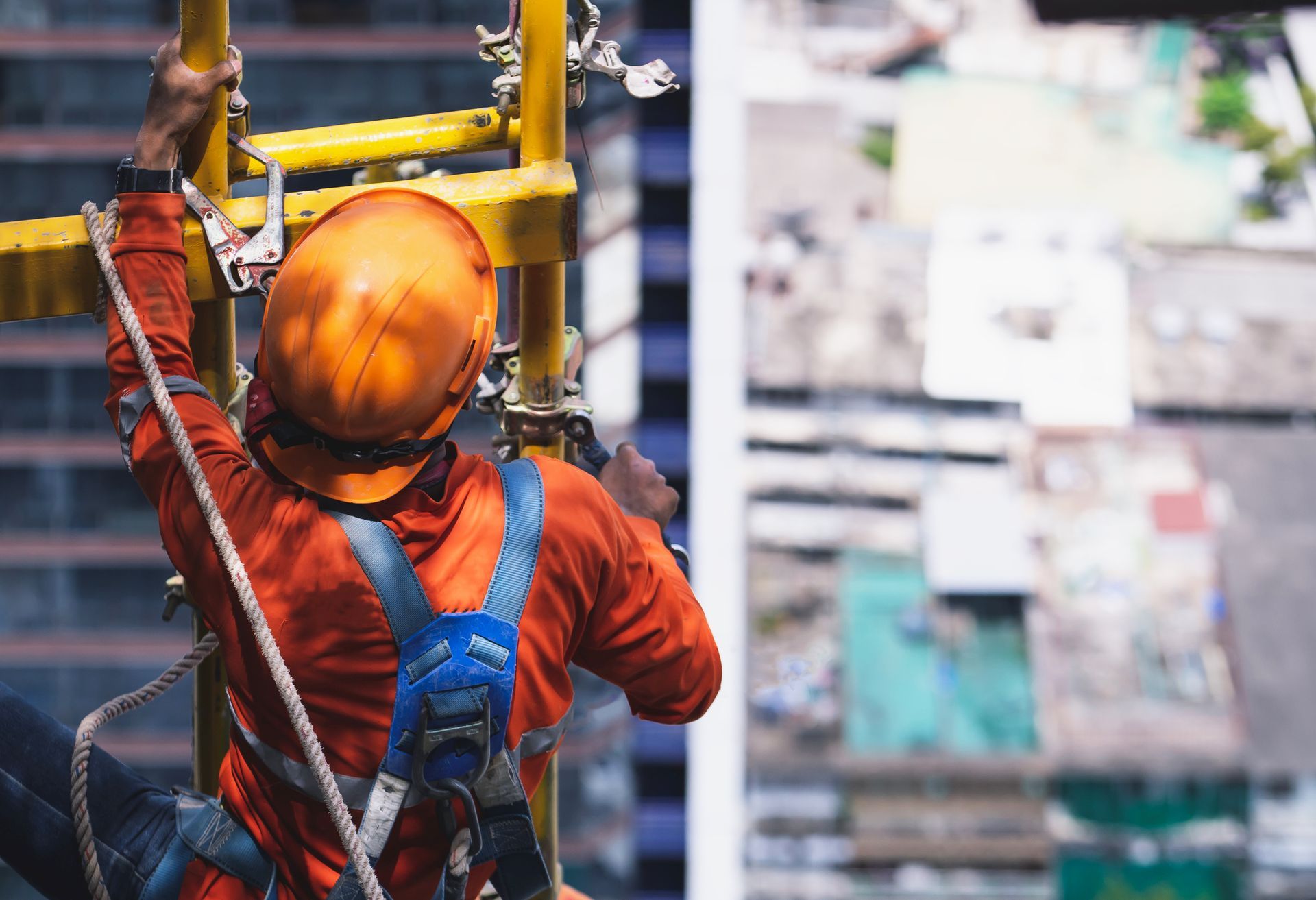 A construction worker is climbing a ladder on top of a building.