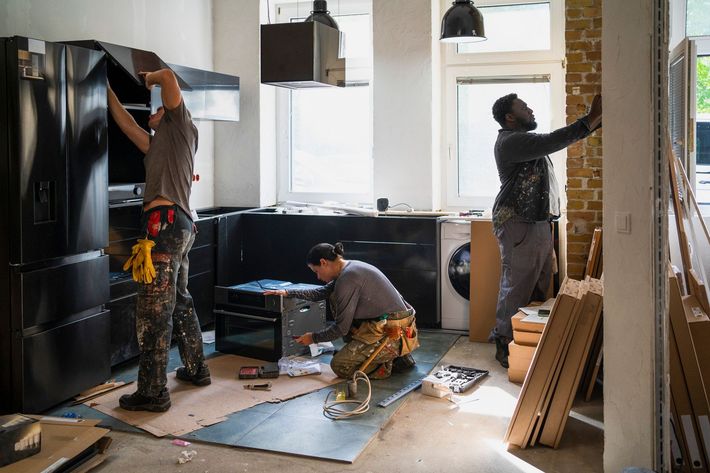 A group of men are working on a kitchen. A group of men are working on a kitchen.