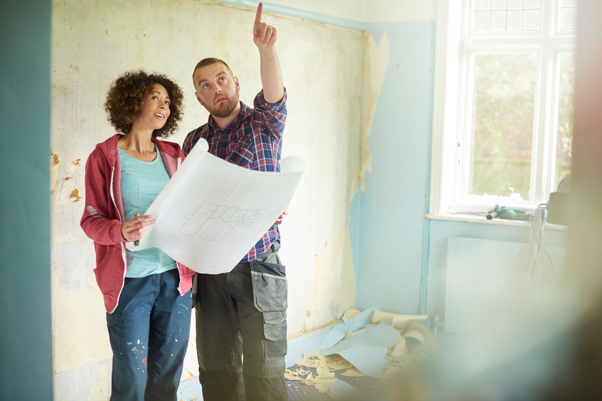 A man and a woman are looking at a blueprint in a room.