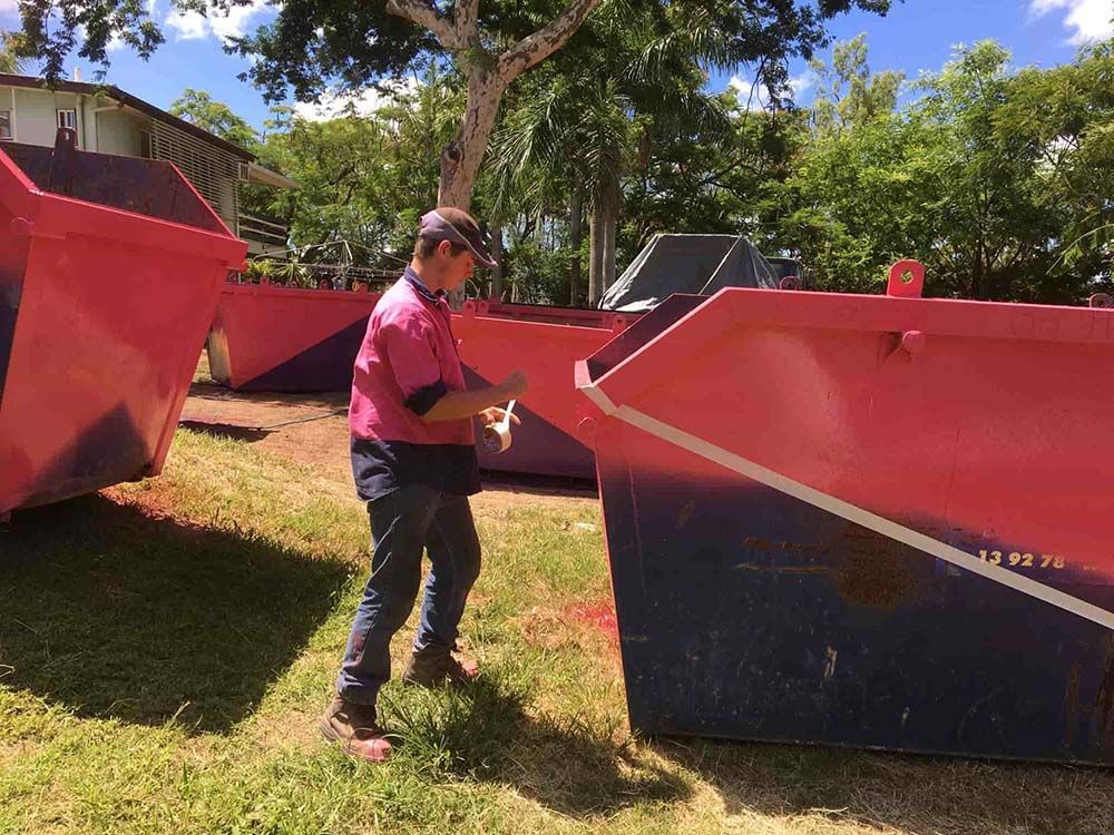 Man In A Pink Shirt Standing Next To A Pink Dumpster — Kanga Bins Qld Pty Ltd In Mulara, QLD