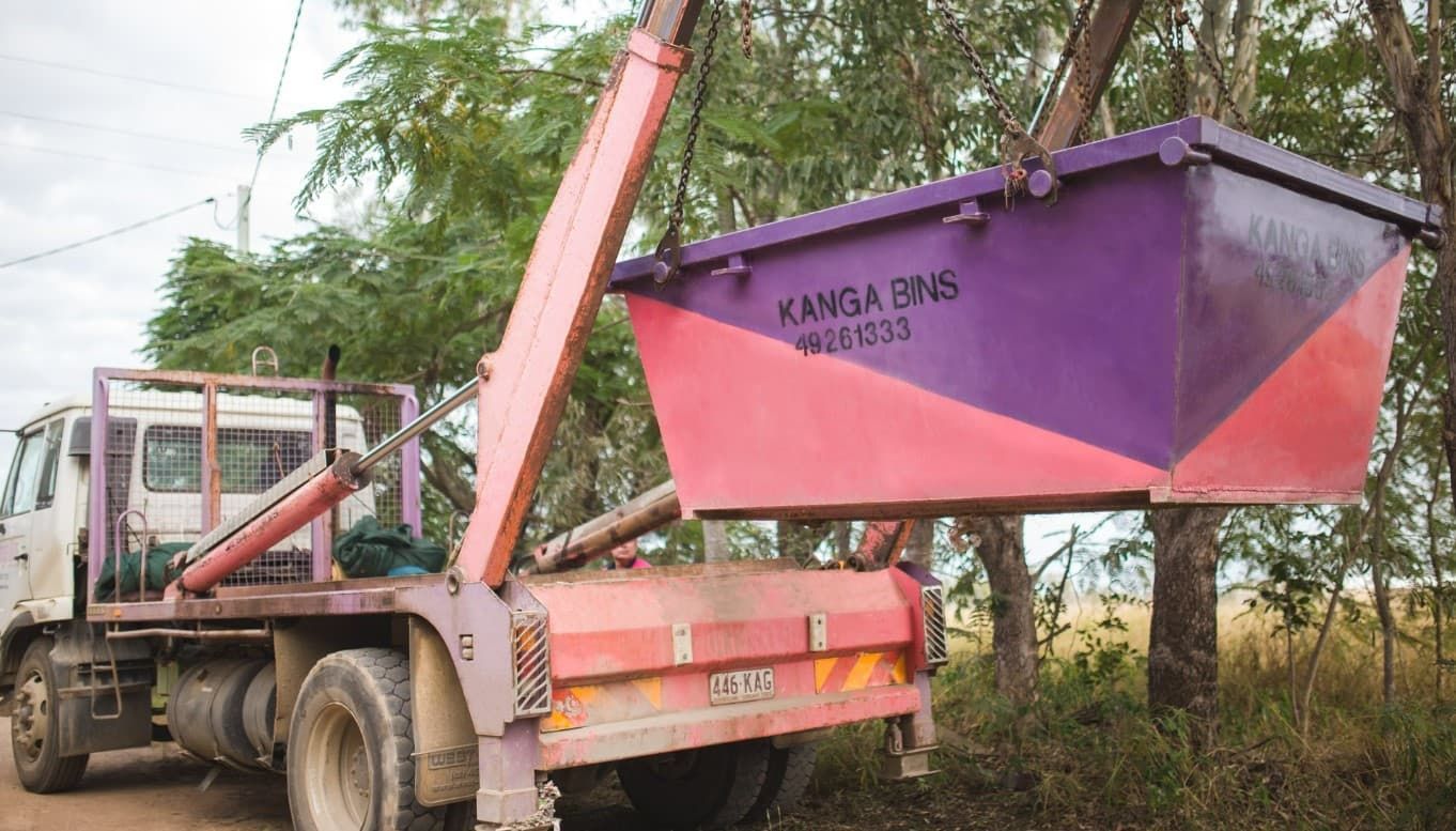 Pink And Purple Dumpster Being Lifted By A Crane — Kanga Bins Qld Pty Ltd In Mulara, QLD