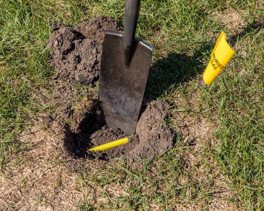 Shovel Digging A Hole In The Ground Next To A Yellow Flag — Kanga Bins Qld Pty Ltd In Mulara, QLD