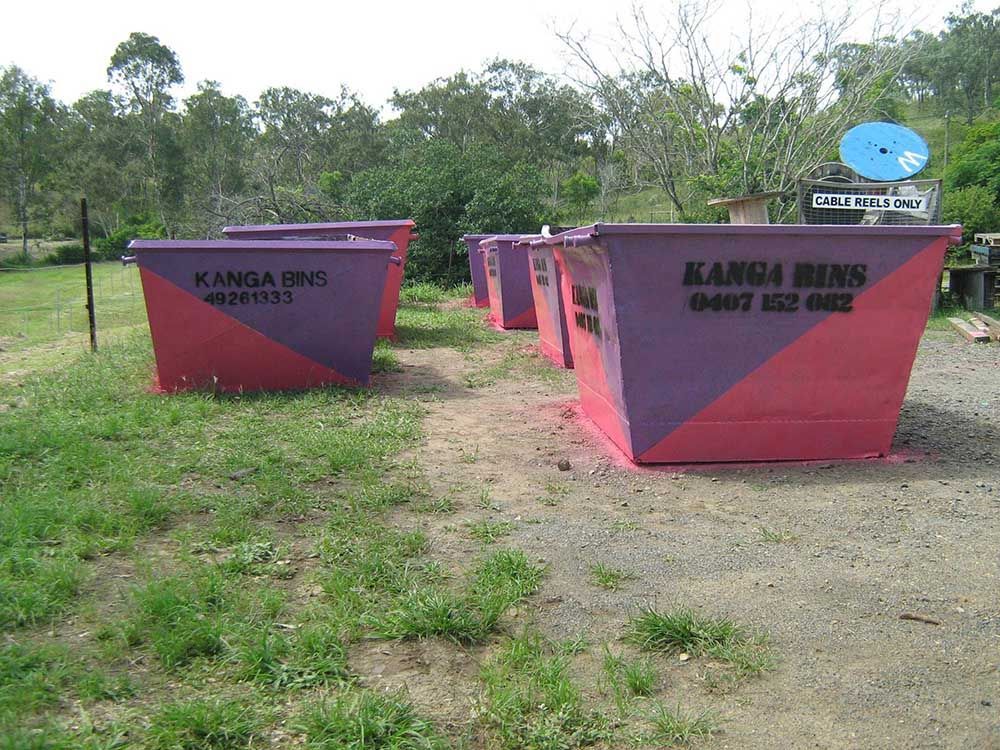 Row Of Pink And Purple Dumpsters With Kanga Bins Written On Them — Kanga Bins Qld Pty Ltd In Mulara, QLD
