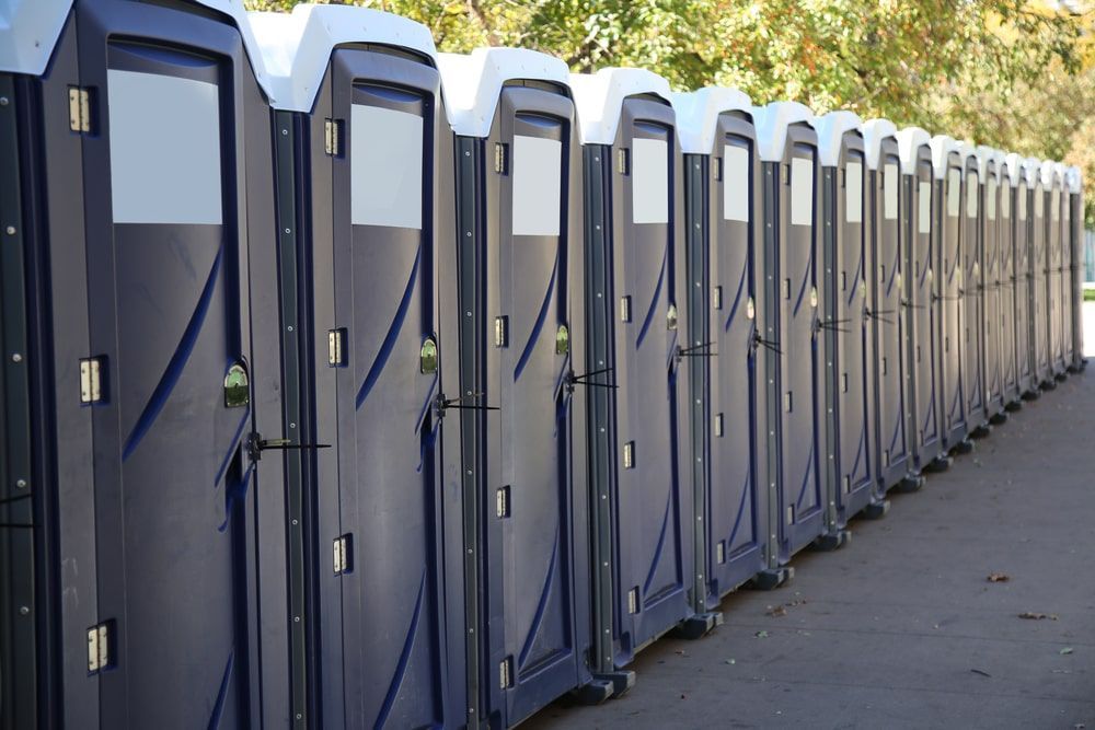 Dark Blue Portable Toilets Lined Up On The Side Of The Road — Kanga Bins Qld Pty Ltd In Mulara, QLD
