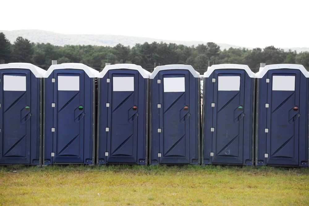 Row Of Dark Blue Portable Toilets Lined Up In A Field — Kanga Bins Qld Pty Ltd In Mulara, QLD