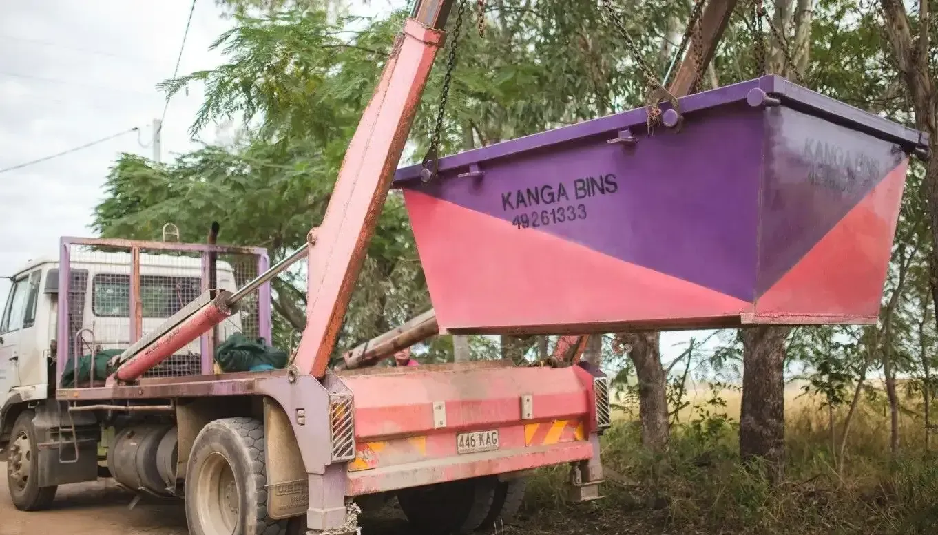 Pink And Purple Dumpster Being Lifted By A Crane — Kanga Bins Qld Pty Ltd In Mulara, QLD