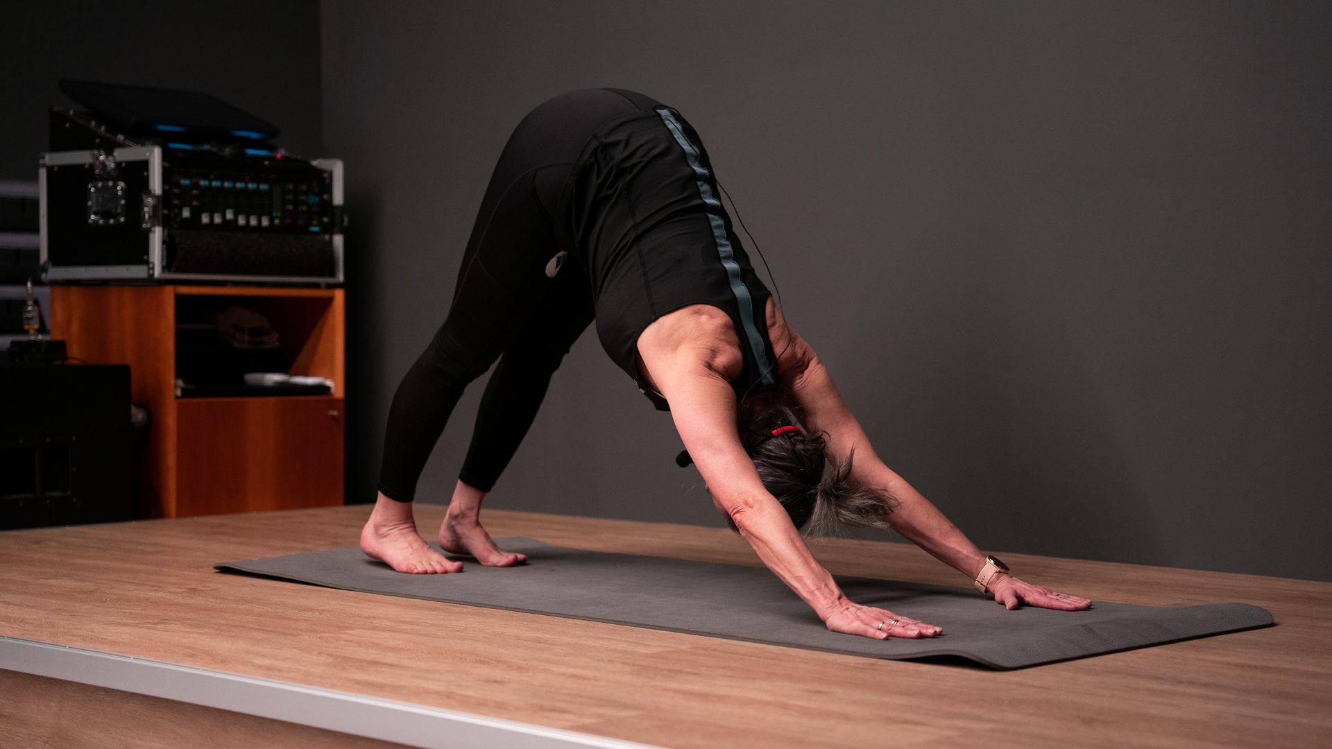 Een vrouw doet een downward dog-yogahouding op een yogamat.
