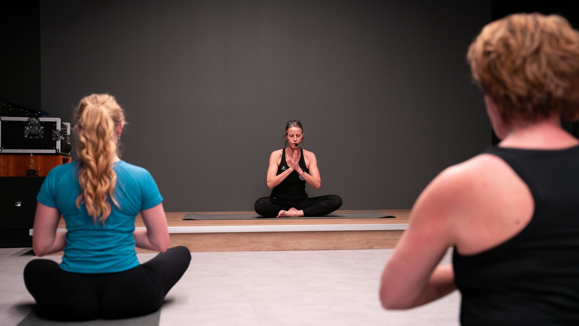 Een groep vrouwen zit in lotushouding op een yogamat.