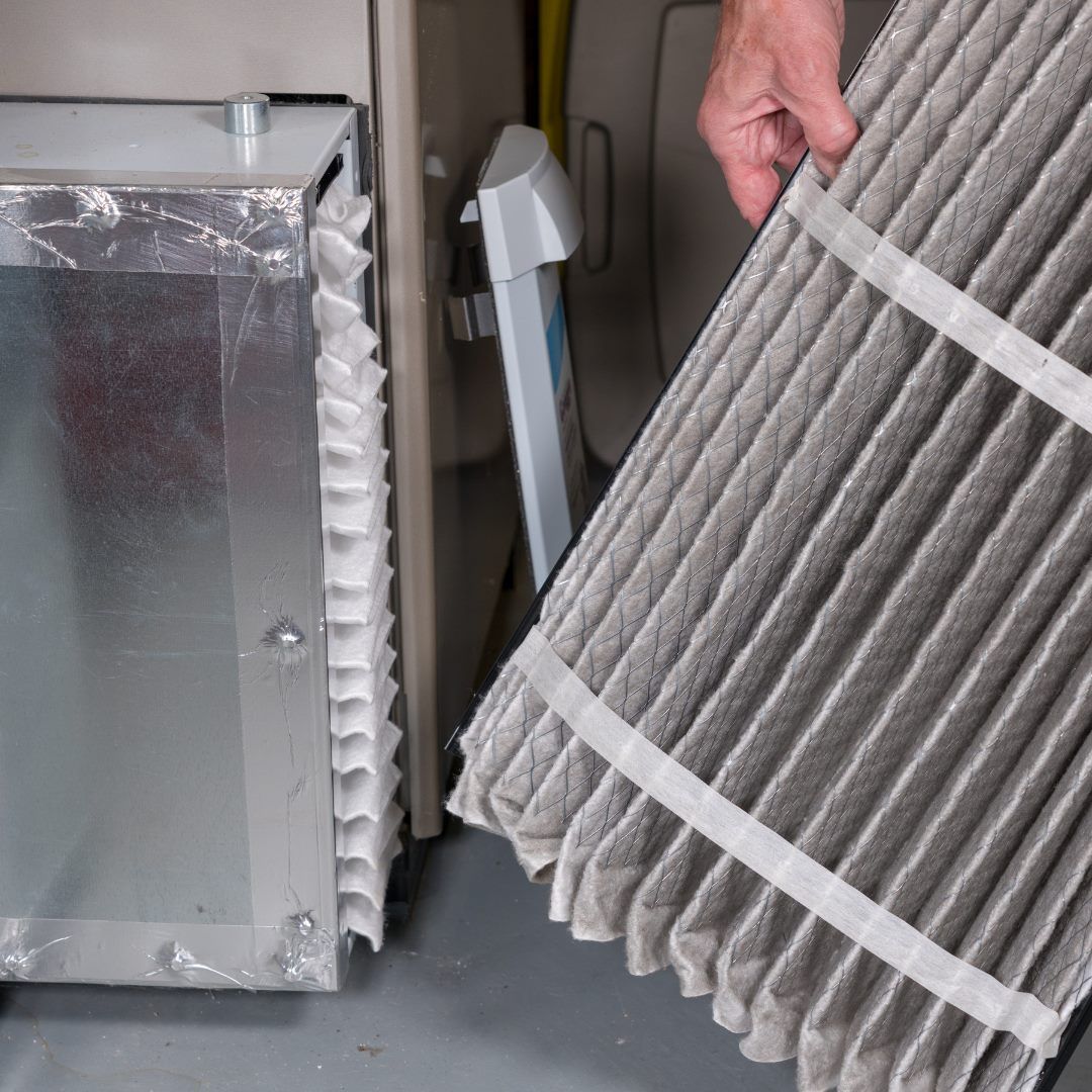 Person replacing a dirty air filter in a furnace.