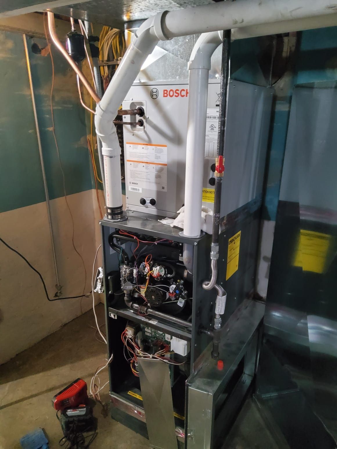 Bosch furnace with open access panel, in a basement setting.