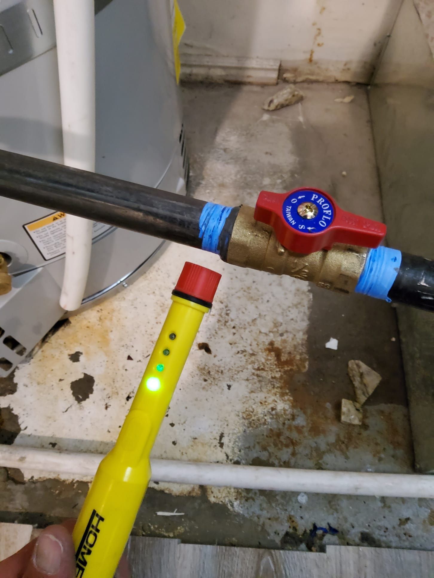 Yellow electrical tester near gas pipe and valve; green light is on.
