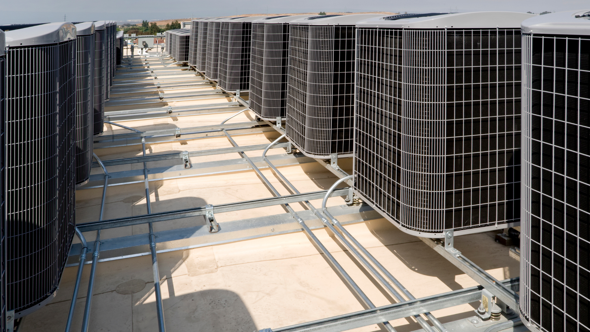 Air conditioning units on a rooftop, with metal supports and wiring.
