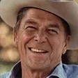 Ronald Reagan smiling, wearing a cowboy hat and denim shirt.