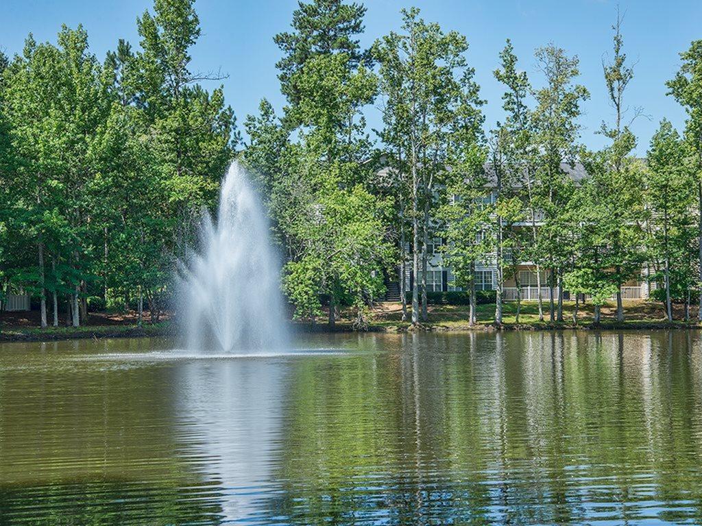 There is a fountain in the middle of a lake surrounded by trees.