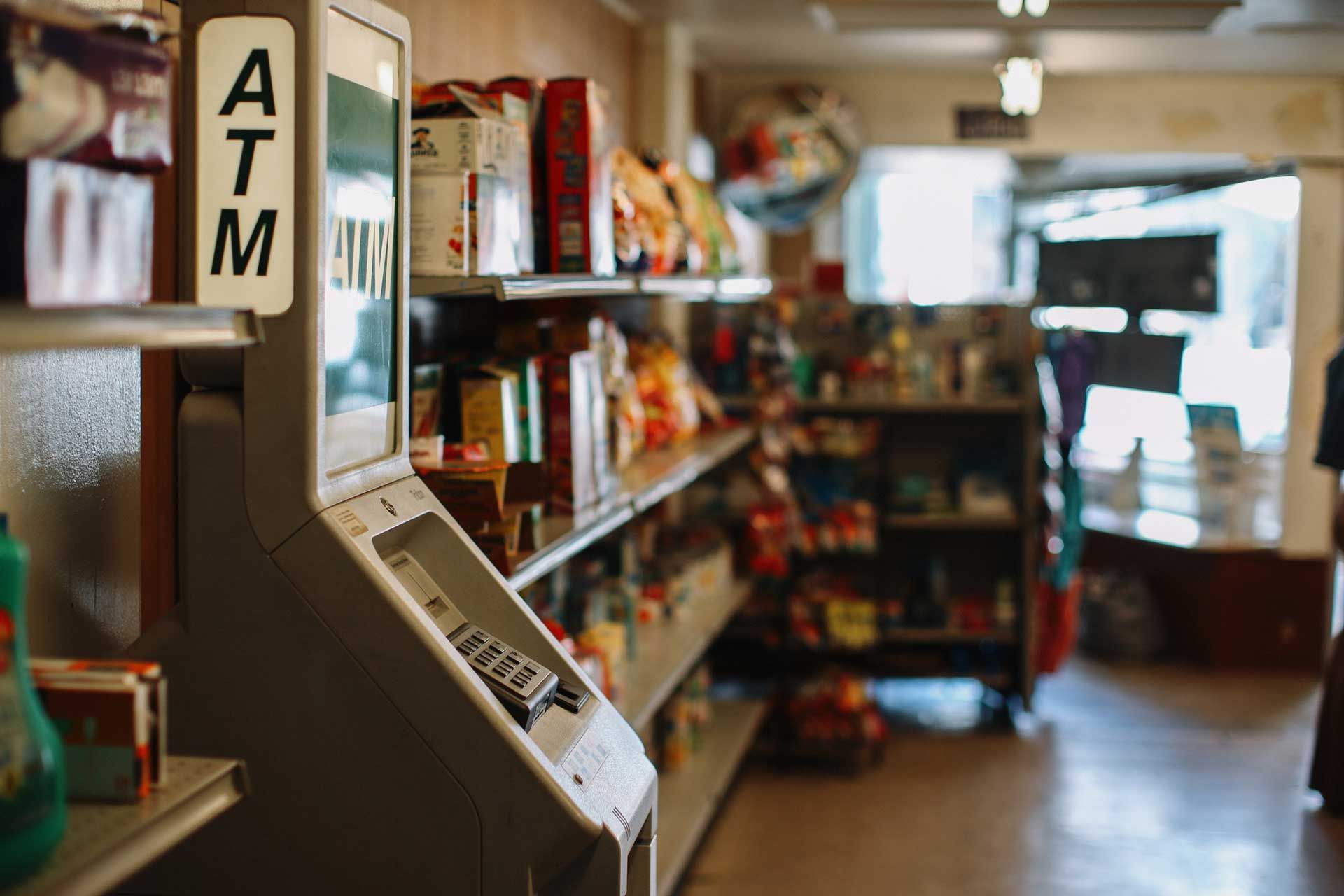 An atm machine is sitting in the middle of a grocery store.
