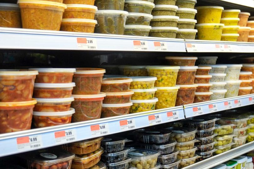 A grocery store shelf filled with plastic containers of food