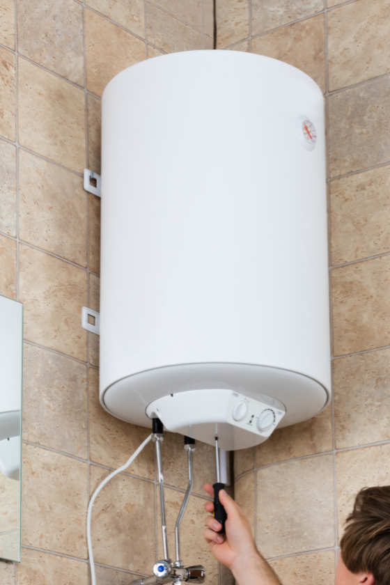 A man is fixing a water heater in a bathroom