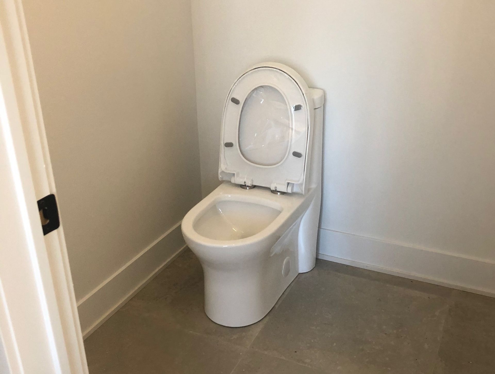 A white toilet is sitting in a bathroom next to a door.