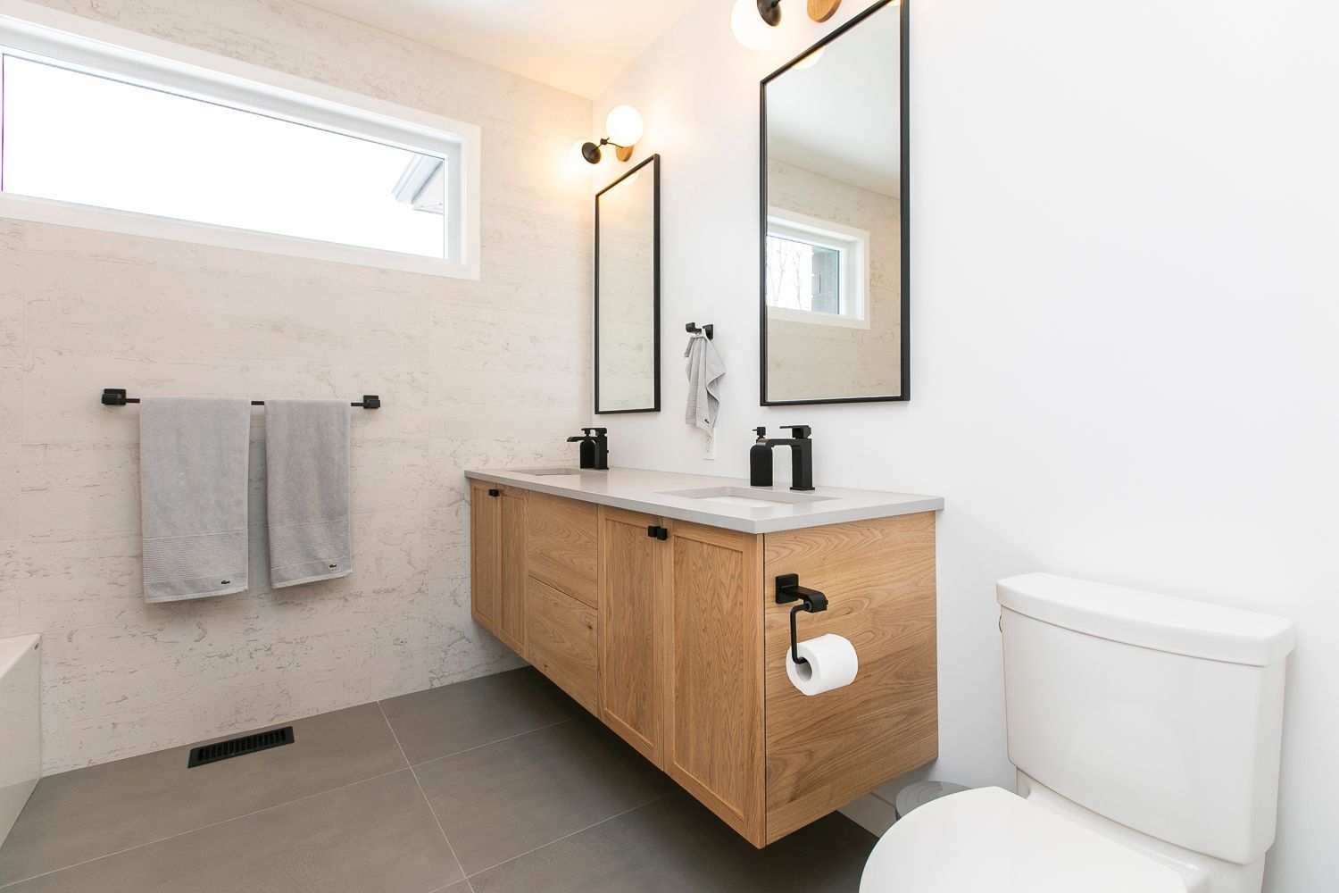 A bathroom with two sinks , a toilet , and two mirrors.