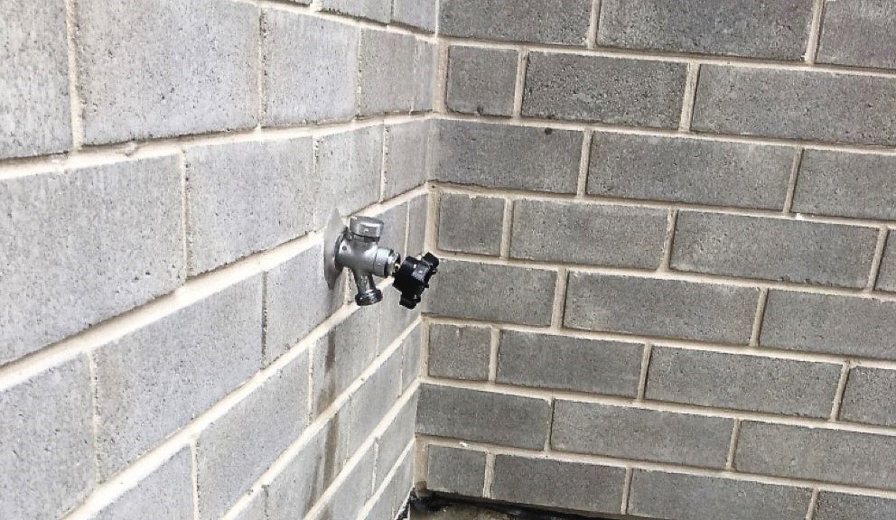 A faucet is attached to a brick wall.
