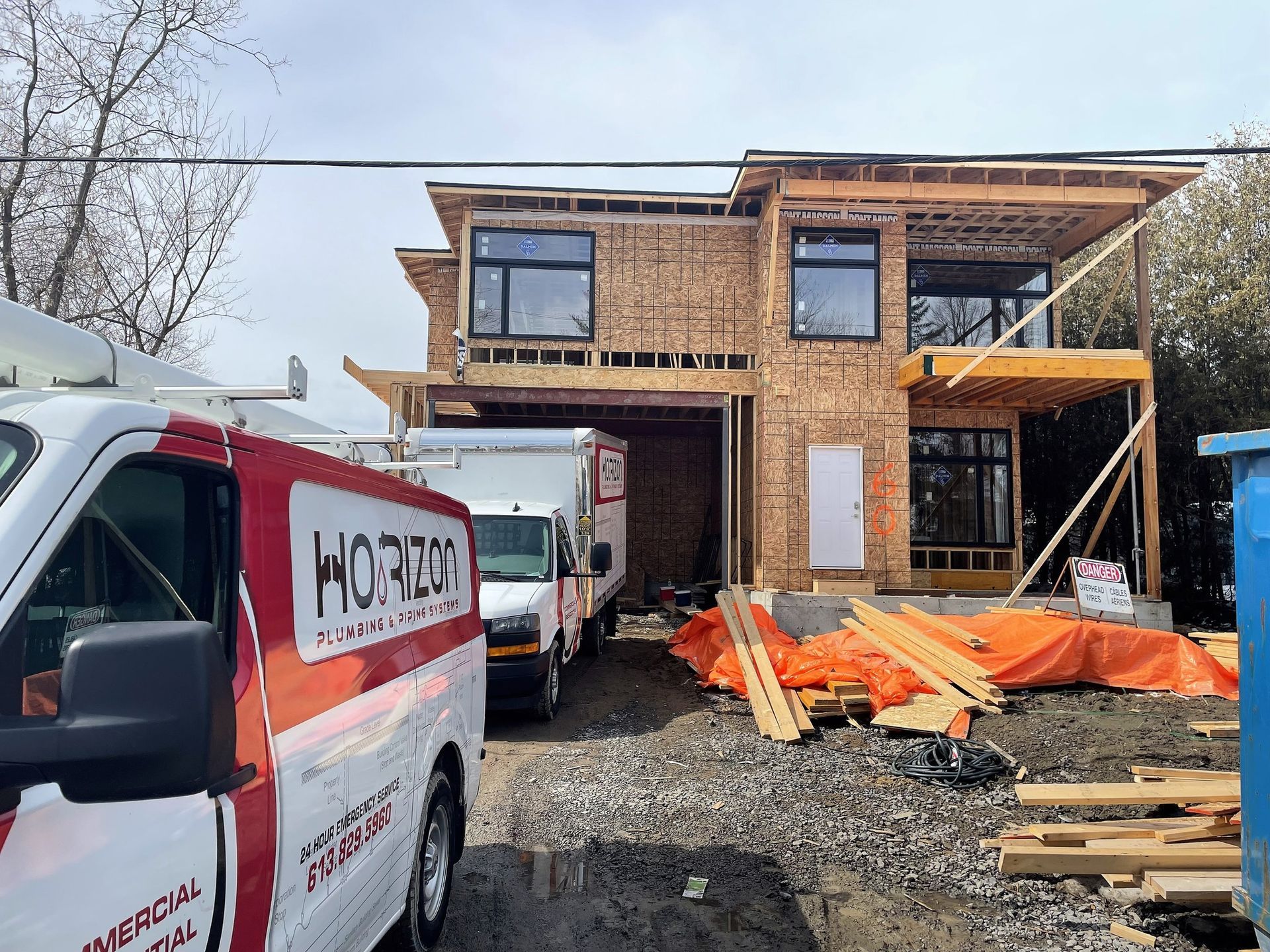 A red and white van is parked in front of a house under construction.
