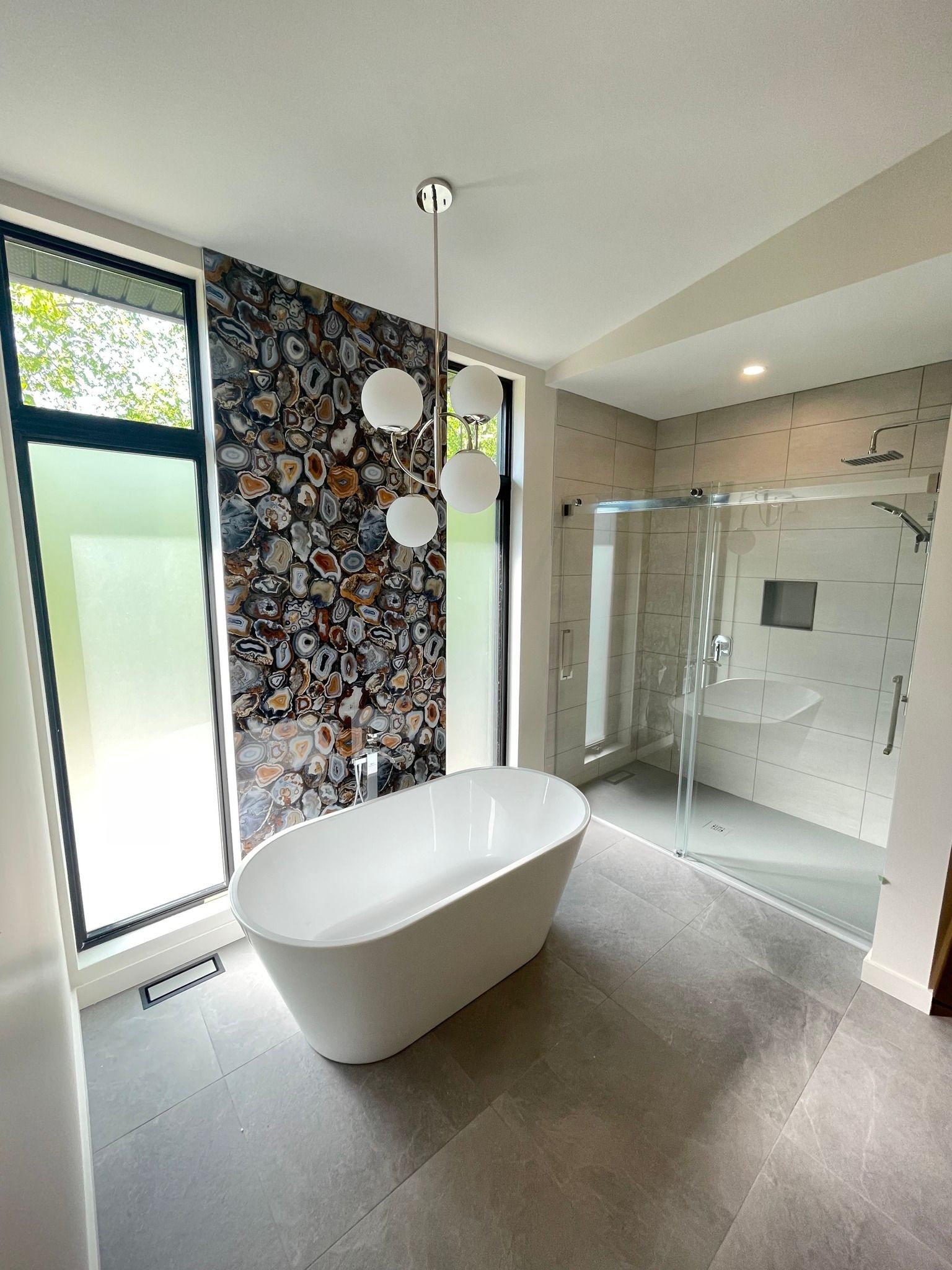 A bathroom with a bathtub , sink , shower and window.
