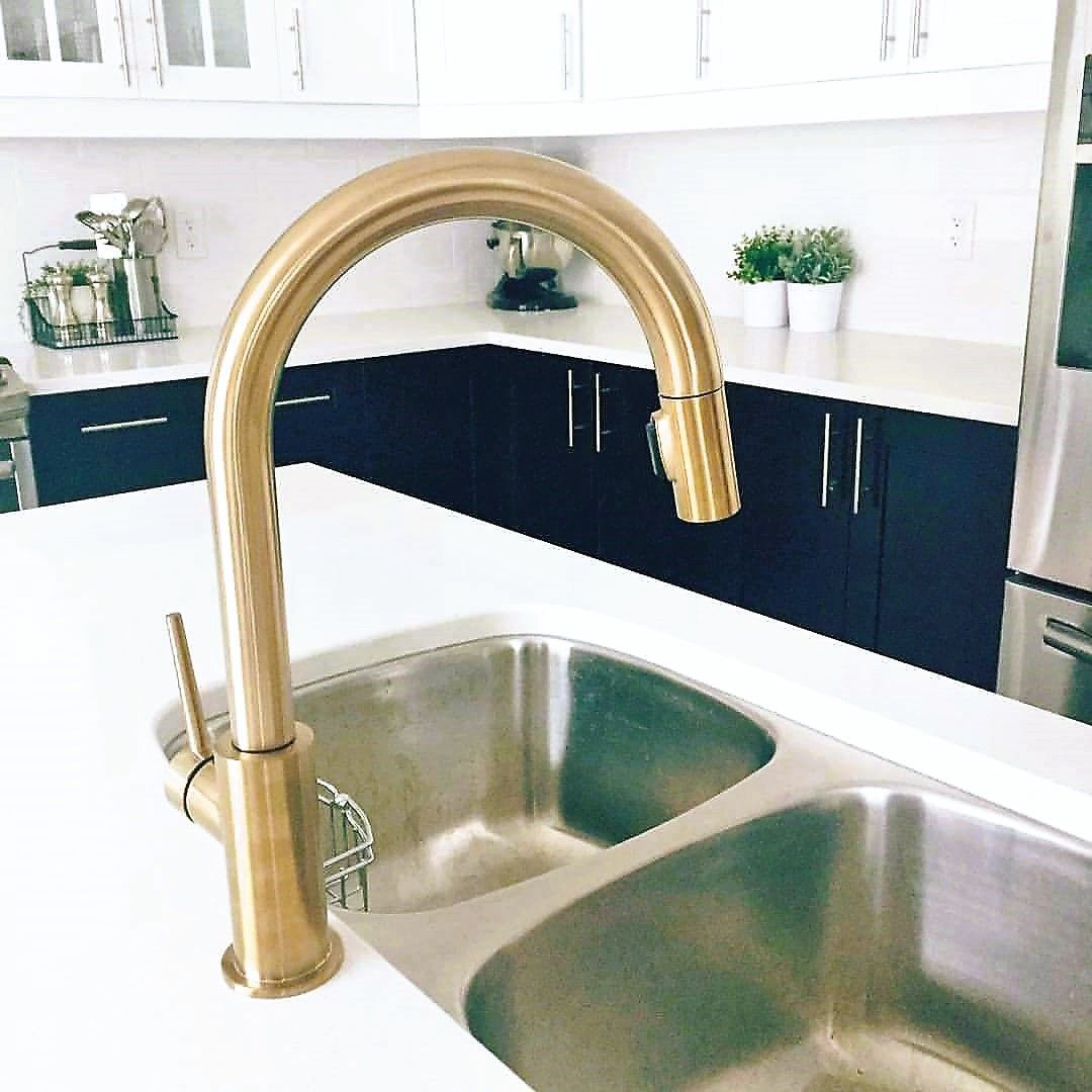 A kitchen with two sinks and a gold faucet