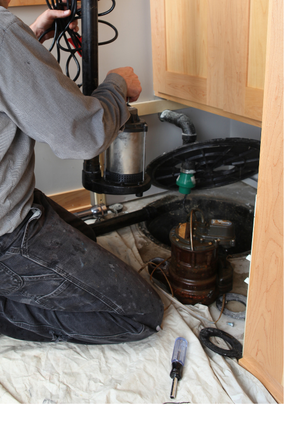 A man is kneeling on the floor working on a vacuum cleaner.