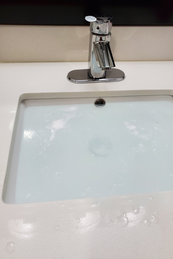 A bathroom sink with a faucet and water coming out of it.