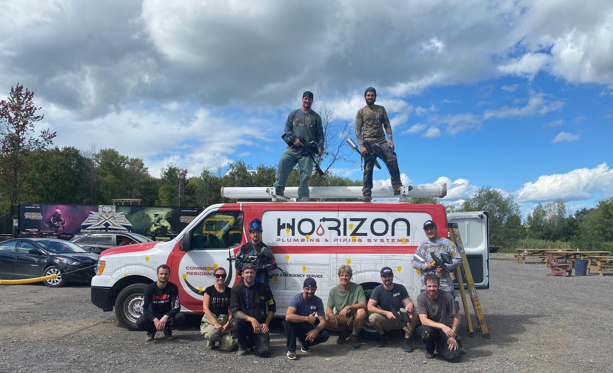 A group of men are posing for a picture in front of a horizon van.