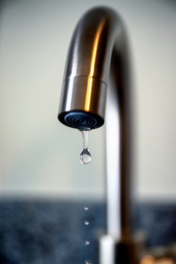 A faucet with a drop of water coming out of it