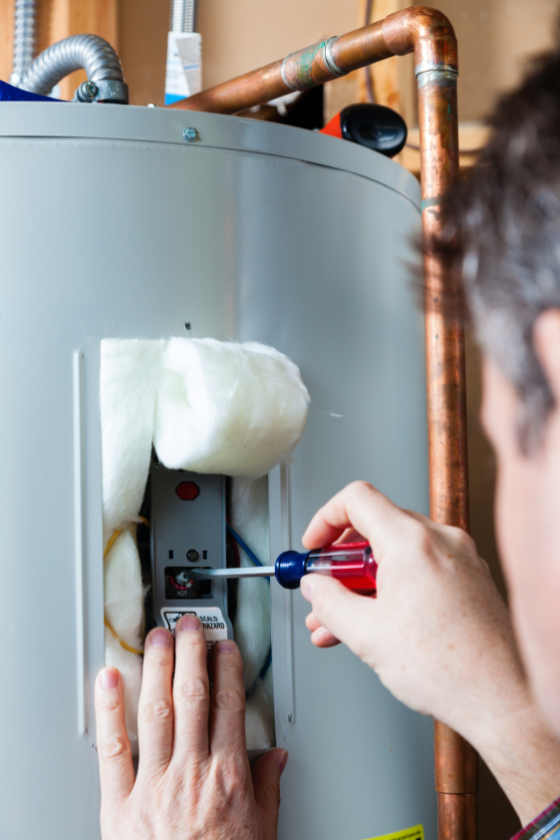 A man is fixing a water heater with a screwdriver.