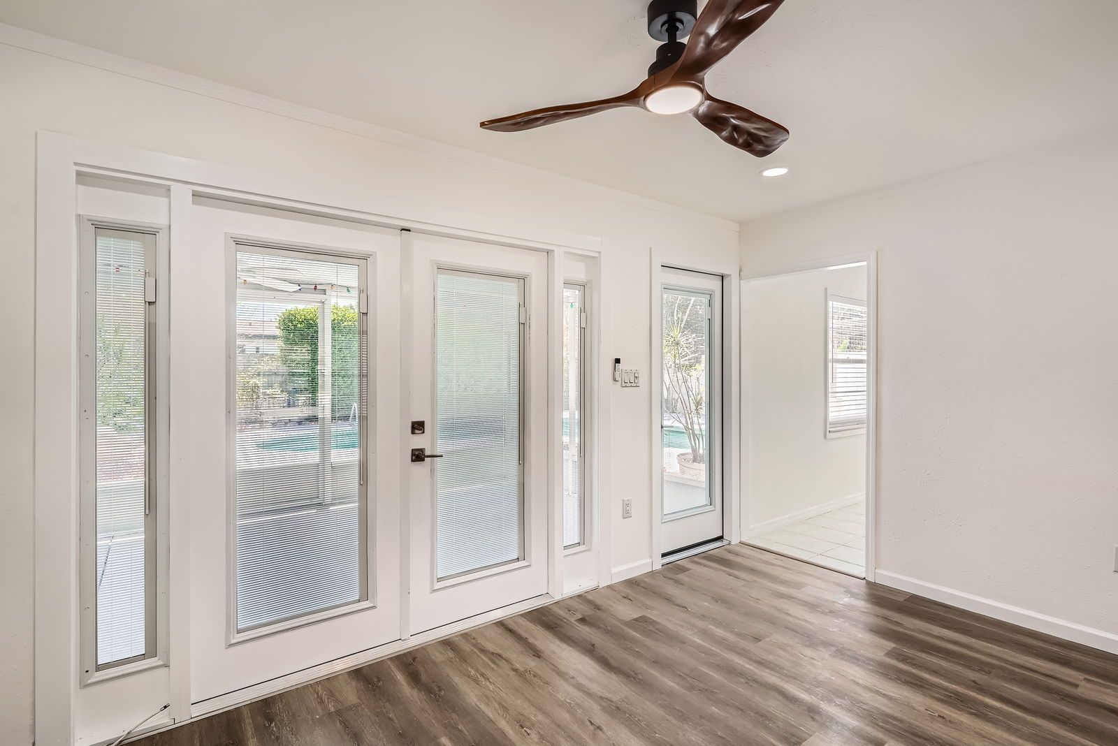 An empty room with a ceiling fan and sliding glass doors.