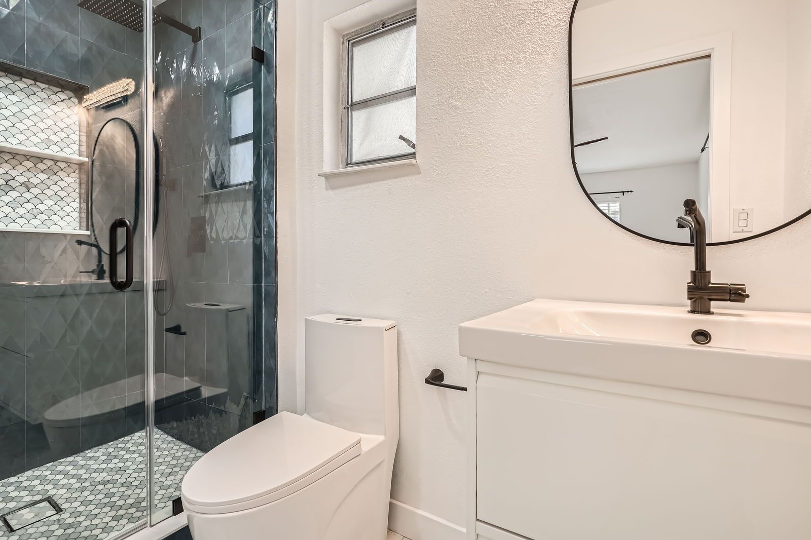 A bathroom with a toilet , sink , shower and mirror.